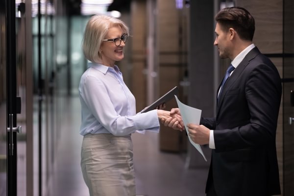 A woman and a man shake hands in a business setting