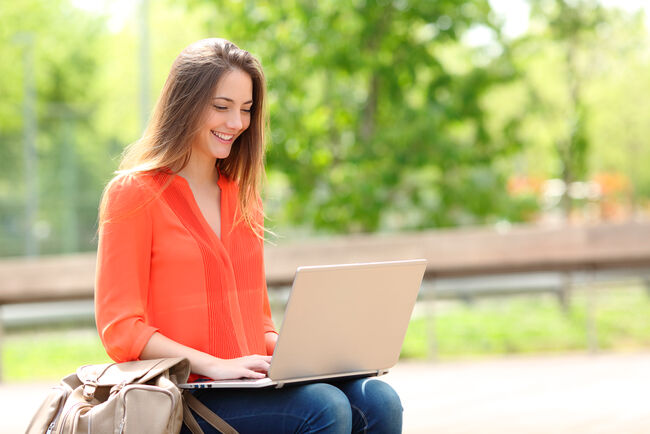 Woman working on laptop in a park.